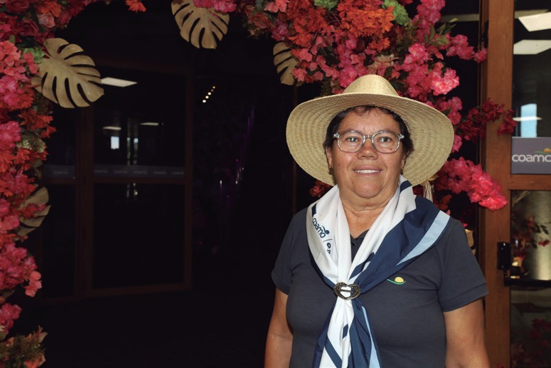 C&eacute;lia Aparecida Onofre, de chap&eacute;u e len&ccedil;o, diante de painel decorado com flores