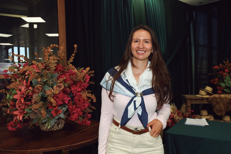 Liriel Vit&oacute;ria Batista da Silva, de len&ccedil;o azul e branco, diante de arranjo de flores
