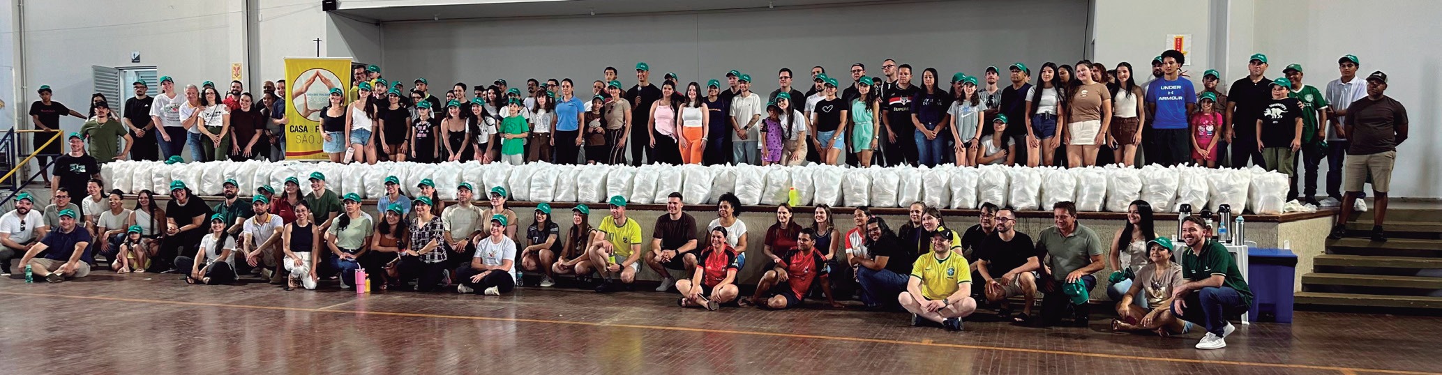 Grupo de funcion&aacute;rios e familiares reunidos no gin&aacute;sio, com as fraldas produzidas &agrave; frente