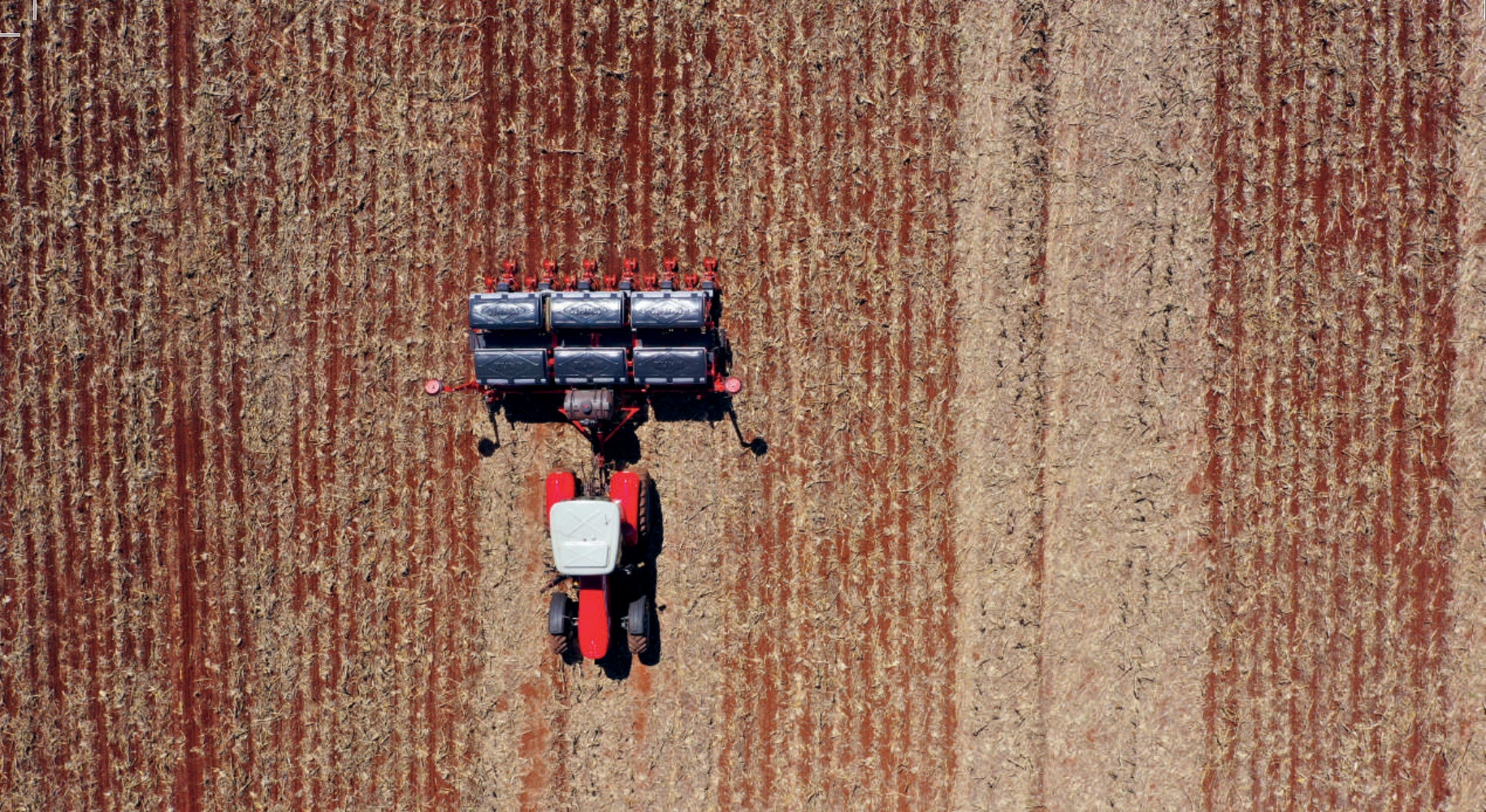 Visão aérea de um trator plantando em uma lavoura de milho colhida