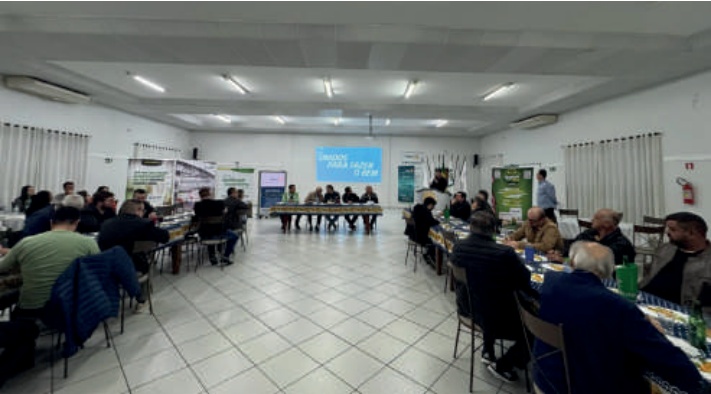 Visão geral de uma sala com pessoas sentadas em mesas durante um evento de formatura.