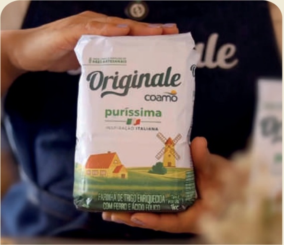 Mão segurando um pacote da Farinha Originale Puríssima Coamo.