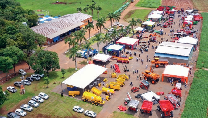 Vista a&eacute;rea da exposi&ccedil;&atilde;o de m&aacute;quinas agr&iacute;colas com tratores e implementos organizados