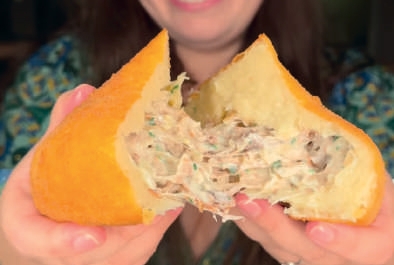 Pessoa segurando duas coxinhas grandes de costela