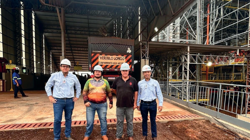 Quatro homens posam para foto em frente a um caminh&atilde;o descarregando gr&atilde;os na nova unidade