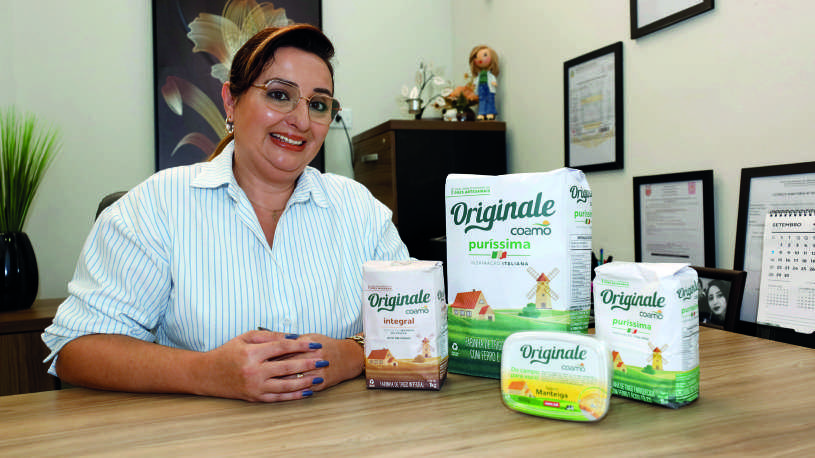 Fabiana Schimidt Doneda sentada em sua mesa de escritório com produtos da linha Originale.