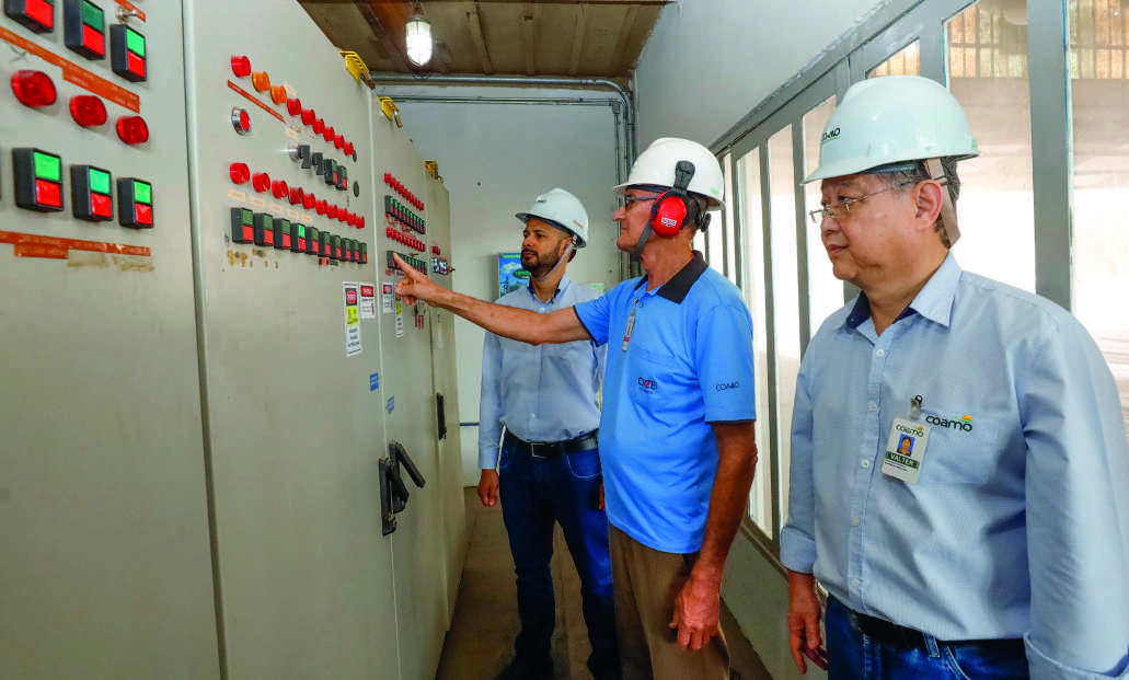 Da esquerda para a direita: Edenilson Carlos de Oliveira, diretor de Logística e Operações, um funcionário da cooperativa e Valter Massashi Yamao, coordenador de Manutenção Elétrica, analisam um painel de controle.